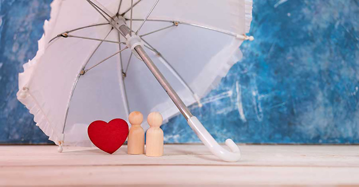 Bild zeigt Paar aus Holz Herz und Schirm für Sicherheit