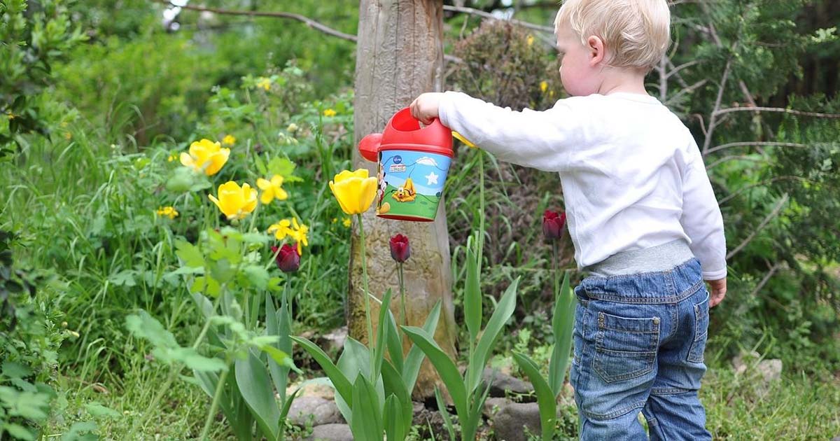 Bild zeigt Kind mit Gießkanne das im Garten spielt