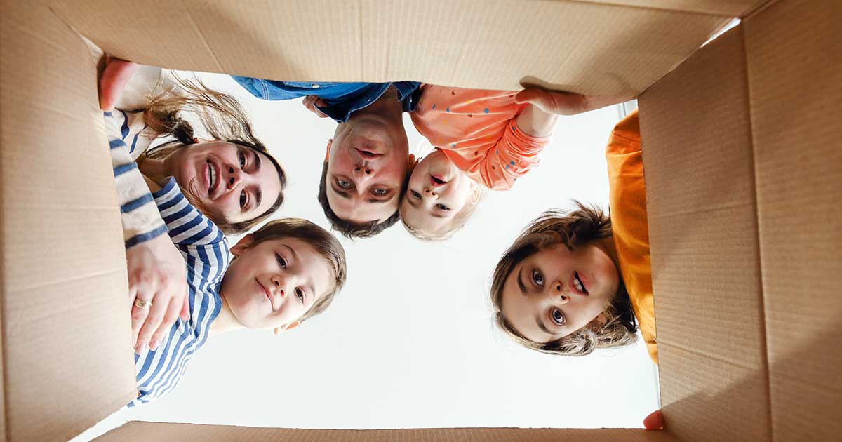 Bild zeigt eine Familie, die in einen Karton schaut