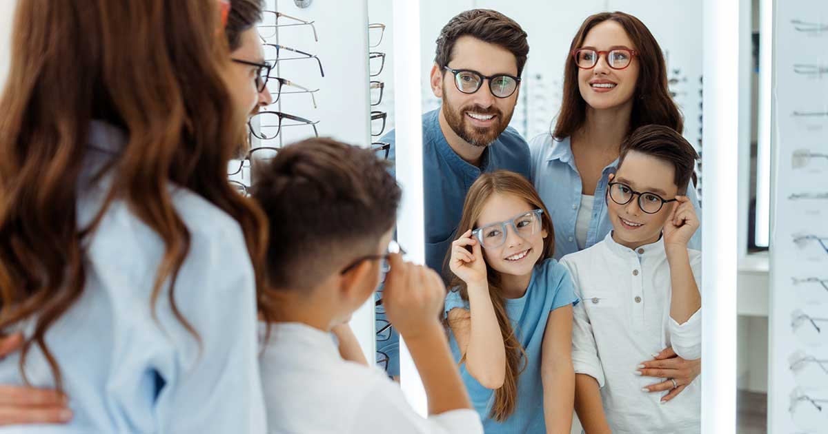Familie probiert gemeinsam Brillen beim Optiker an