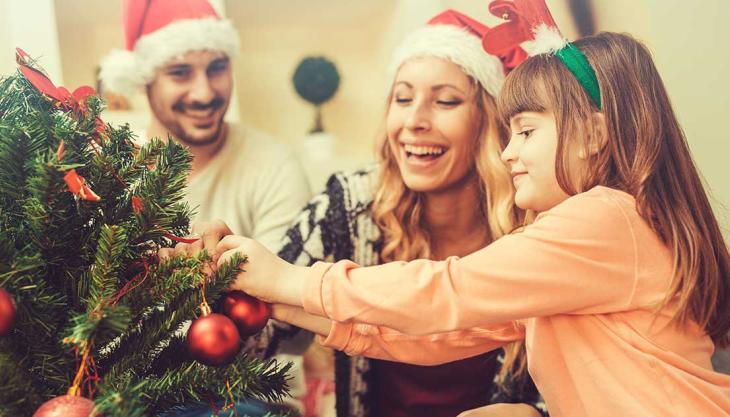 Familie schmückt gemeinsam den Weihnachtsbaum im Advent