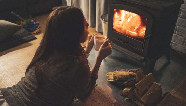 Frau am Kamin nimmt sich eine Auszeit mit einer Tasse Tee