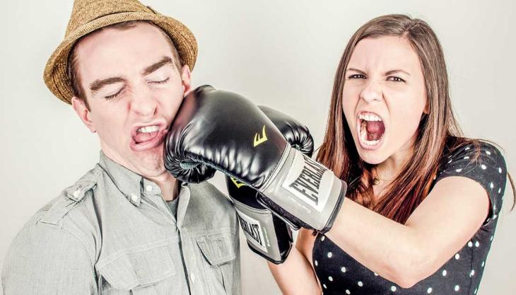 Frau mit Boxhandschuh schlägt Mann ins Gesicht – symbolischer Beziehungsstreit