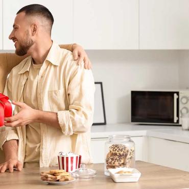 Paar in der Küche mit kleinem Geschenk – aufmerksamer Moment in der Beziehung
