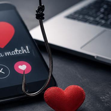 Smartphone mit Dating-App, Herz und Angelhaken als Symbol für Catfishing