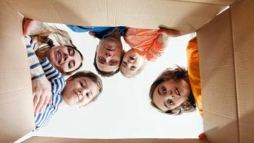 Bild zeigt eine Familie, die in einen Karton schaut