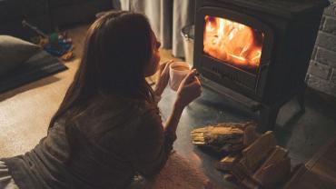 Frau am Kamin nimmt sich eine Auszeit mit einer Tasse Tee