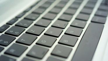 Nahaufnahme einer Laptop-Tastatur mit schrägem Blickwinkel, Fokus auf den Buchstabentasten.