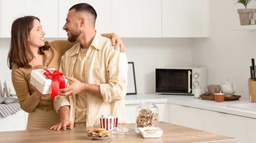 Paar in der Küche mit kleinem Geschenk – aufmerksamer Moment in der Beziehung