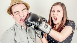 Frau mit Boxhandschuh schlägt Mann ins Gesicht – symbolischer Beziehungsstreit