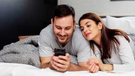 Paar schaut gemeinsam auf ein Smartphone im Bett