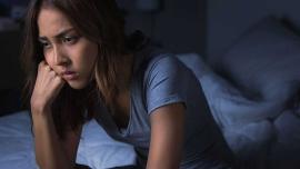 Trauernde Frau sitzt nachdenklich auf dem Bett und verarbeitet einen Verlust in der Familie