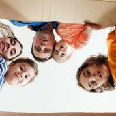 Bild zeigt eine Familie, die in einen Karton schaut