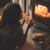Frau am Kamin nimmt sich eine Auszeit mit einer Tasse Tee