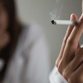 Mann raucht eine Zigarette, Partnerin im Hintergrund wirkt genervt und distanziert