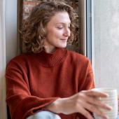 Frau genießt ruhigen Selfcare-Moment mit einer Tasse Tee am Fenster