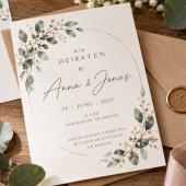 Elegante Hochzeitseinladung mit floralen Motiven, Eheringen, Umschlägen und rosafarbenem Seidenband auf einem Holztisch.