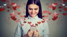 Junge Frau liest lächelnd eine Nachricht auf dem Smartphone – Online-Dating mit Herzsymbolen