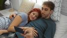 Paar liegt im Bett und schaut gemeinsam auf ein Smartphone – symbolisiert digitale Intimität und Nähe.