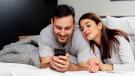 Paar schaut gemeinsam auf ein Smartphone im Bett